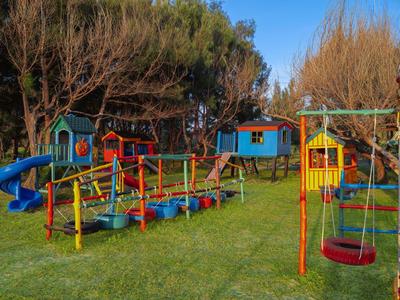 Kolorowy plac zabaw dla dzieci z huśtawkami, zjeżdżalniami i konstrukcjami do wspinaczki na trawie.