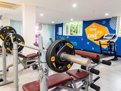 Nowoczesna siłownia z ławką do ćwiczeń i kolorowym wzorem na ścianie w hotelu.