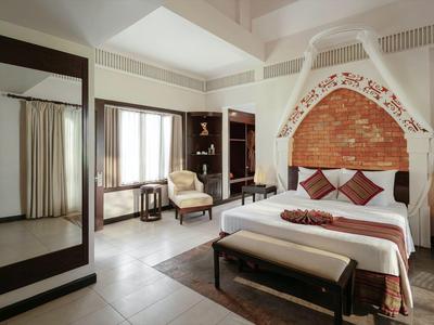 Jasny pokój hotelowy z łóżkiem podwójnym, miejscem do siedzenia, dużym lustrem i oknem z zasłonami.