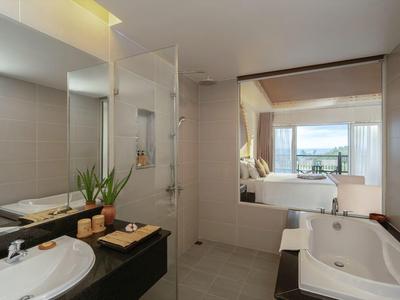 Łazienka hotelowa z prysznicem, wanną, umywalką i widokiem na salon z oknem i krajobrazem.