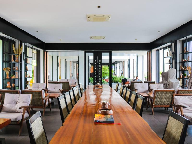 Jasna jadalnia z długim drewnianym stołem, miejscami do siedzenia, nowoczesnym wystrojem i dużymi oknami.