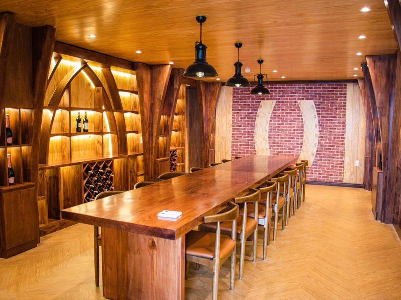 Długi drewniany stół z krzesłami w pokoju z drewnianymi panelami i półkami na książki.