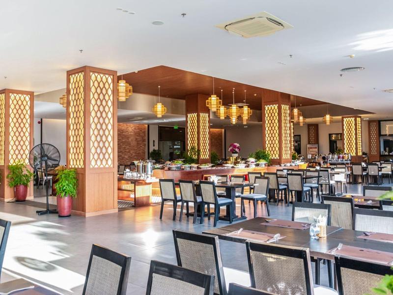 Przestronna jadalnia z nowoczesnymi stołami, krzesłami i ciepłym drewnianym wystrojem.