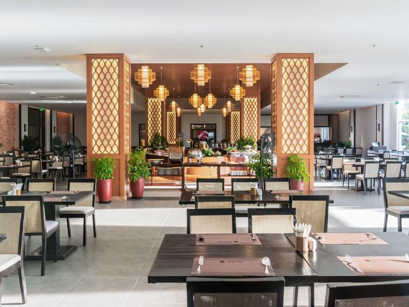 Jasna, nowoczesna restauracja hotelowa z wieloma krzesłami i dekoracyjnymi latarniami.