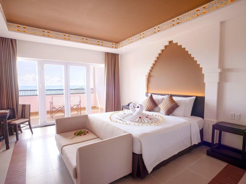 Jasny pokój hotelowy z dużym łóżkiem, balkonem i widokiem na morze
