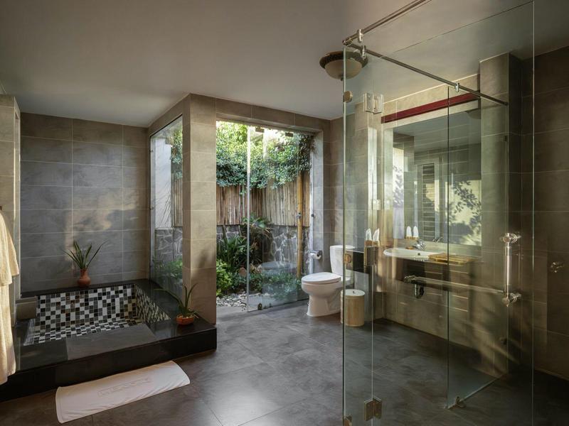 Nowoczesna łazienka z dużym prysznicem, wolnostojącą wanną i oknami od podłogi do sufitu z widokiem na ogród