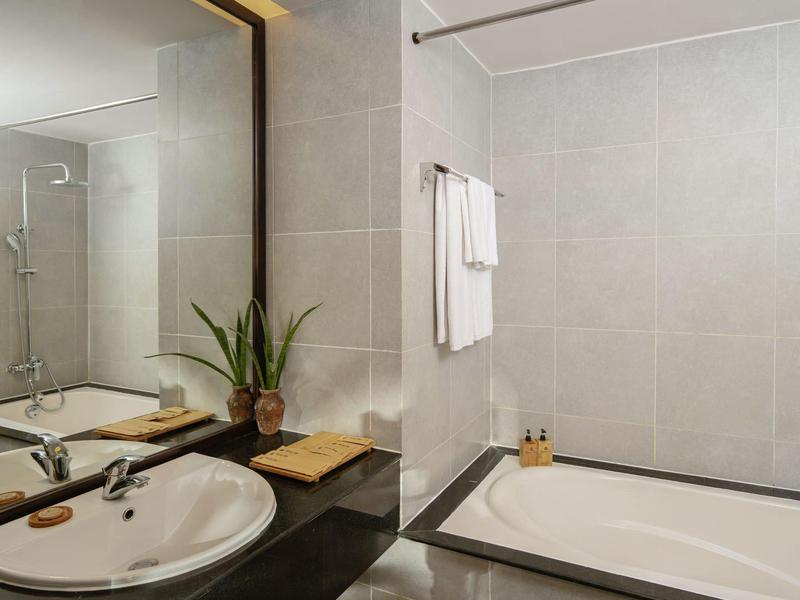 Nowoczesna łazienka z wanną, umywalką i dużymi lustrami o ciepłym świetle.