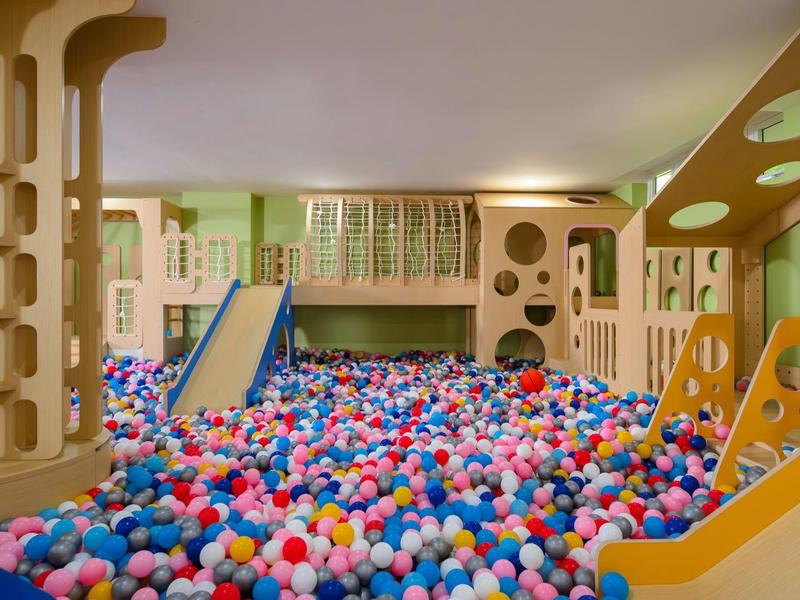 Kolorowa sala zabaw z basenem kulkowym, zjeżdżalniami i kreatywnymi ścianami i kolumnami.