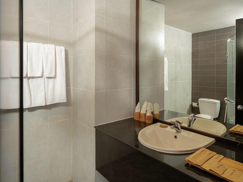 Nowoczesna łazienka z dużym lustrem, umywalką i ciemnoszarymi płytkami.