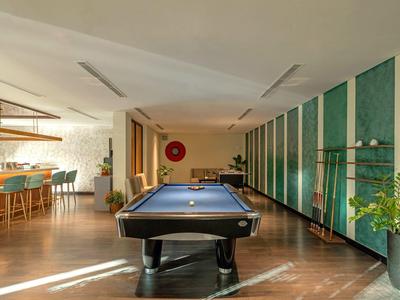 Nowoczesny pokój rekreacyjny z stołem bilardowym, barem i wygodnymi miejscami do siedzenia.