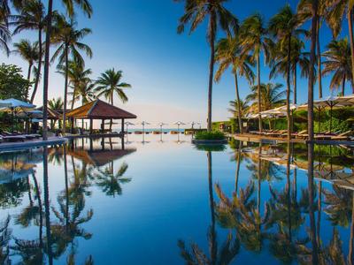 Piscina tranquilla con palme e vista sul mare sotto un cielo sereno.