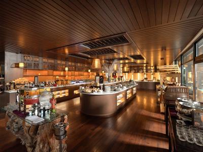 Nowoczesny bar hotelowy z eleganckim wystrojem, drewnianym sufitem, przytulnym oświetleniem i ladą.