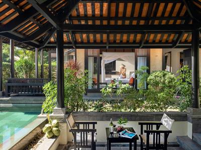 Terrazza coperta con posti a sedere vicino a una piscina e vista su una camera d'hotel con tende.