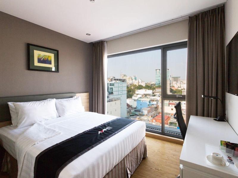 Modernes Schlafzimmer mit großem Bett, weißen Wänden, Schreibtisch und großem Fenster mit Stadtblick.