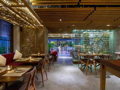 Moderner Restaurantinnenraum mit Holzbalkendecke, gemusterten Wänden, Weinregal und elegant gedeckten Tischen.