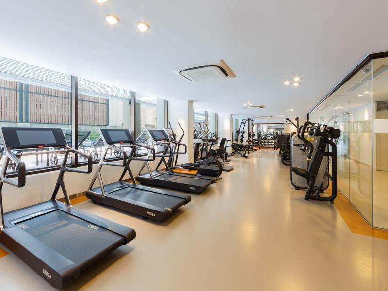 Großer Fitnessraum mit Laufbändern, Crosstrainern und heller, offener Raumgestaltung.