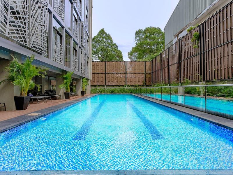 Moderner Außenpool mit klarem blauem Wasser, umgeben von Holzdeck und Glasgeländer.