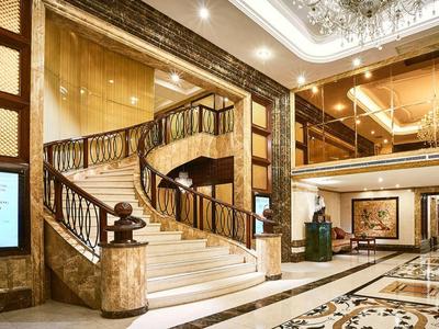 Luxuriöse Hotellobby mit Marmorfußboden, goldener Spiraltreppe und eleganter Deckenbeleuchtung.