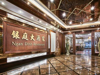 Luxuriöser Hotel- oder Restaurant-Eingang mit glänzendem Marmor, Holzverkleidung und asiatischer Schrift.