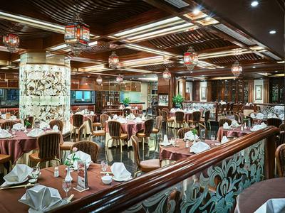 Großes Restaurant mit elegant gedeckten Tischen, dunklem Holz und warmem Licht.