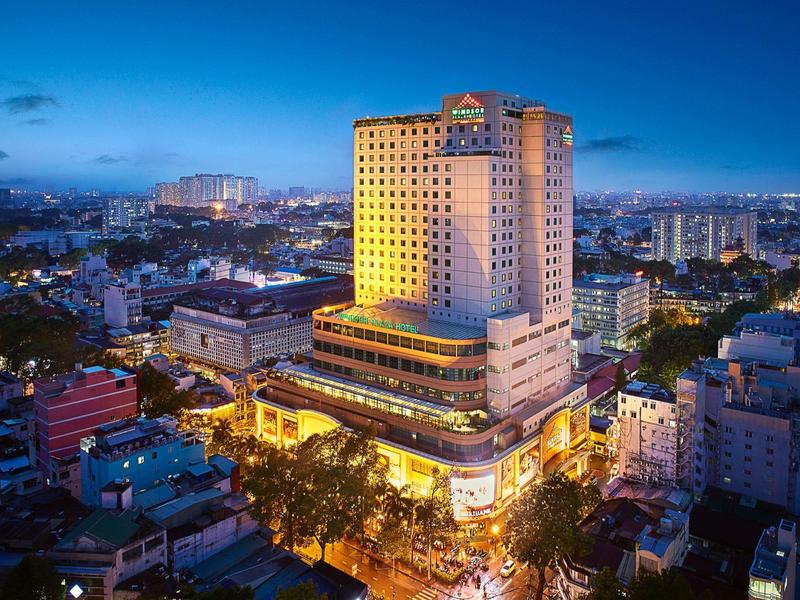 Hochhaus bei Nacht mit gelb beleuchteten Fenstern, umgeben von weiteren Gebäuden und Straßen.