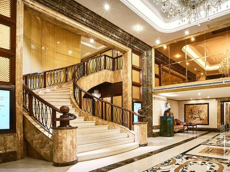 Luxuriöse Hotellobby mit Marmorfußboden, goldener Spiraltreppe und eleganter Deckenbeleuchtung.