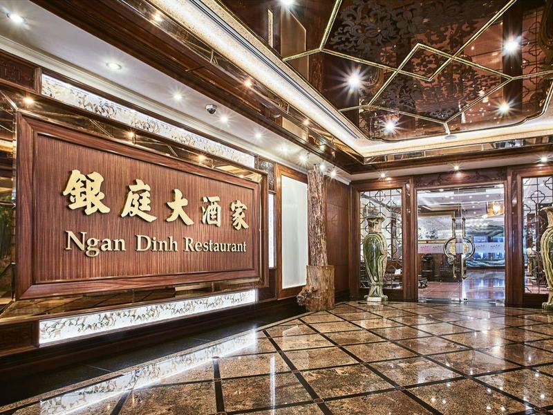 Luxuriöser Hotel- oder Restaurant-Eingang mit glänzendem Marmor, Holzverkleidung und asiatischer Schrift.