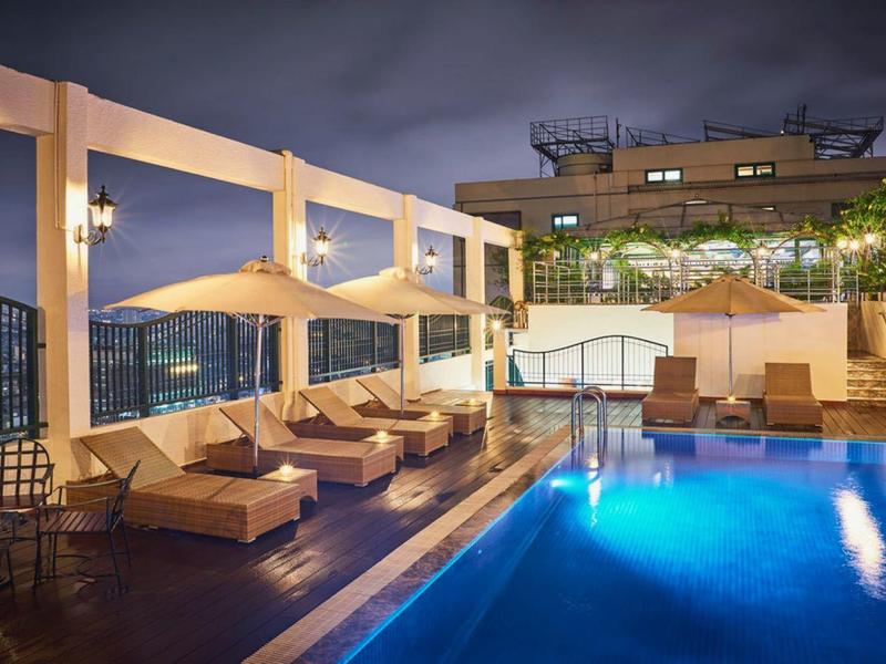 Moderner Außenpool bei Nacht mit Liegestühlen, Pergola und stimmungsvoller Beleuchtung.