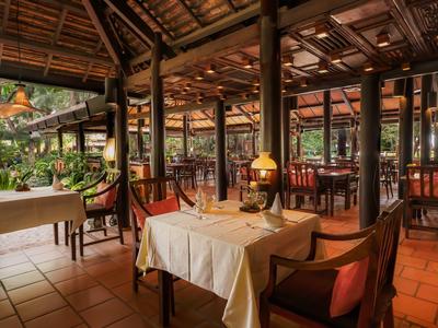 Restaurant cosy avec plafond en bois et éclairage chaleureux dans un cadre tropical.
