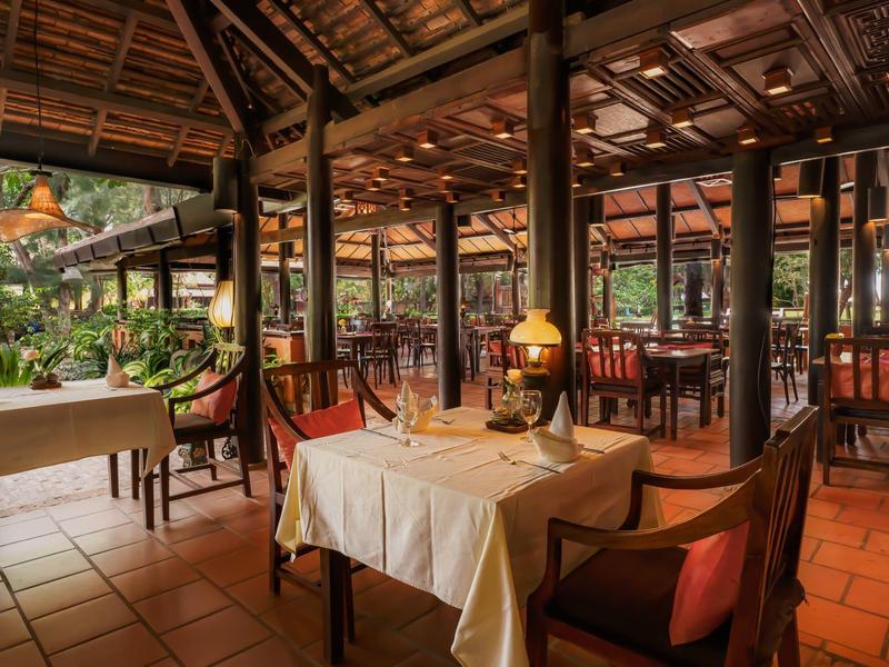 Restaurant cosy avec plafond en bois et éclairage chaleureux dans un cadre tropical.
