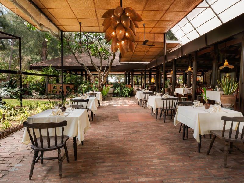 Restaurant lumineux avec nappes blanches et vue sur un jardin.