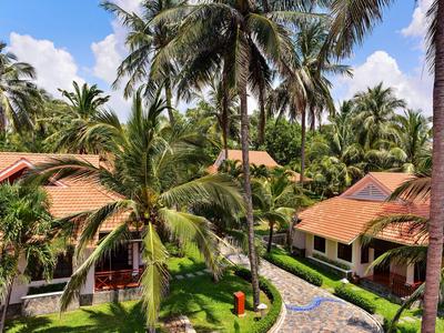 Bungalow dell'hotel in ambiente tropicale con palme e sentiero lastricato sotto un cielo azzurro