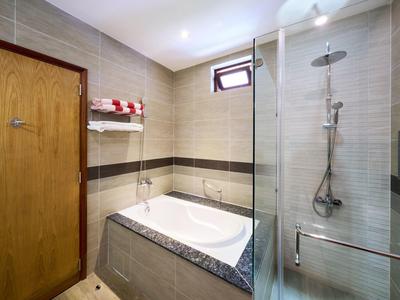 Baño moderno y luminoso con bañera y ducha separada de vidrio en una habitación de hotel.