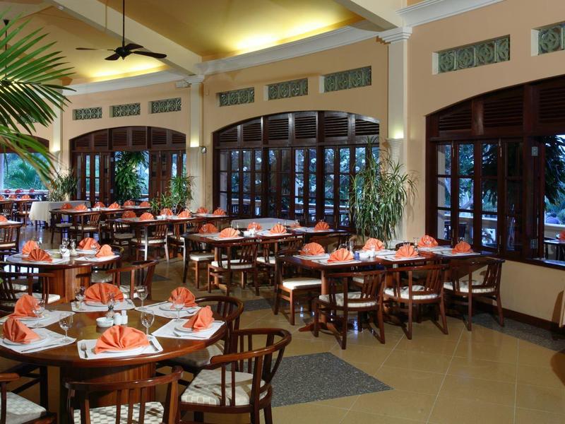 Amplio comedor de hotel con mesas decoradas y grandes ventanas que permiten la luz natural.