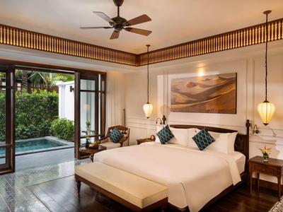 Modernes Schlafzimmer mit großem Bett, Deckenventilator, hängenden Lampen und Zugang zur Terrasse.