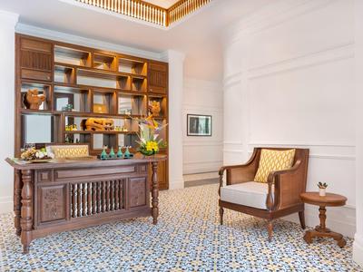 Elegantes Büro mit dunklem Holztisch, braunem Bücherregal, Sessel und gemusterter Fliesenboden.