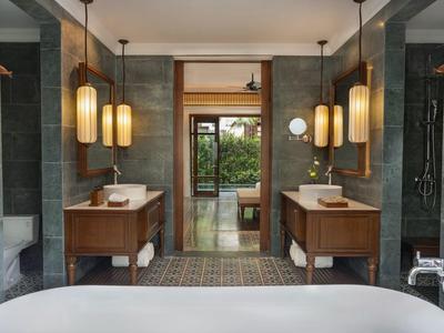 Moderner Badraum mit Doppelwaschbecken, Holzschränken und großen Hängelampen.