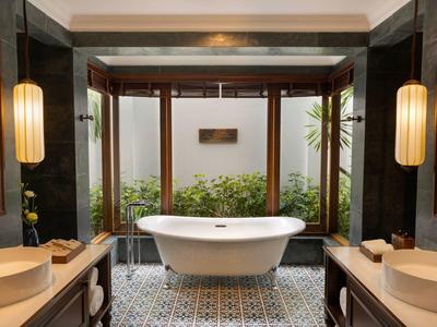 Luxuriöses Badezimmer mit freistehender weißer Badewanne, Holzakzenten und großen Fenstern.