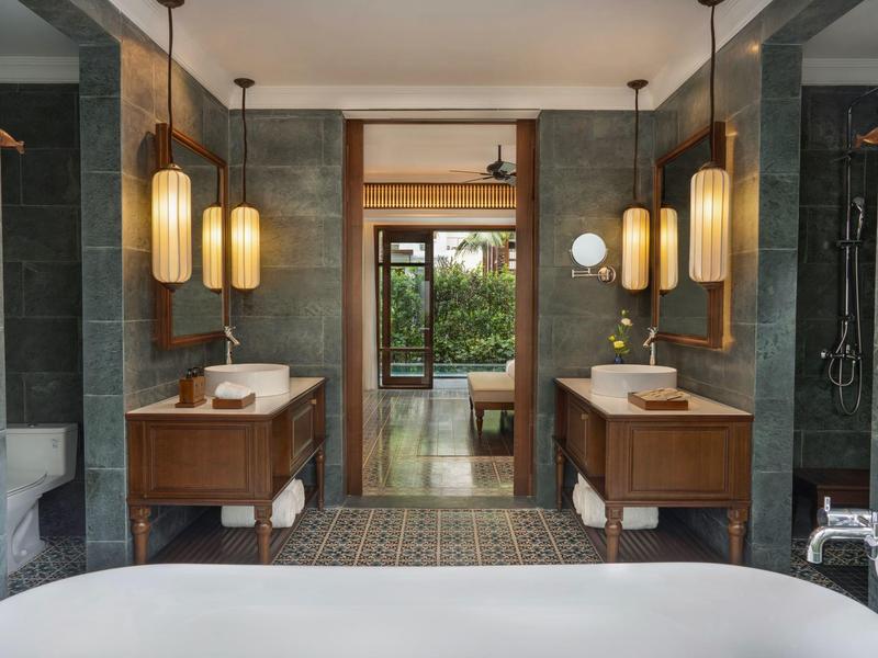 Moderner Badraum mit Doppelwaschbecken, Holzschränken und großen Hängelampen.