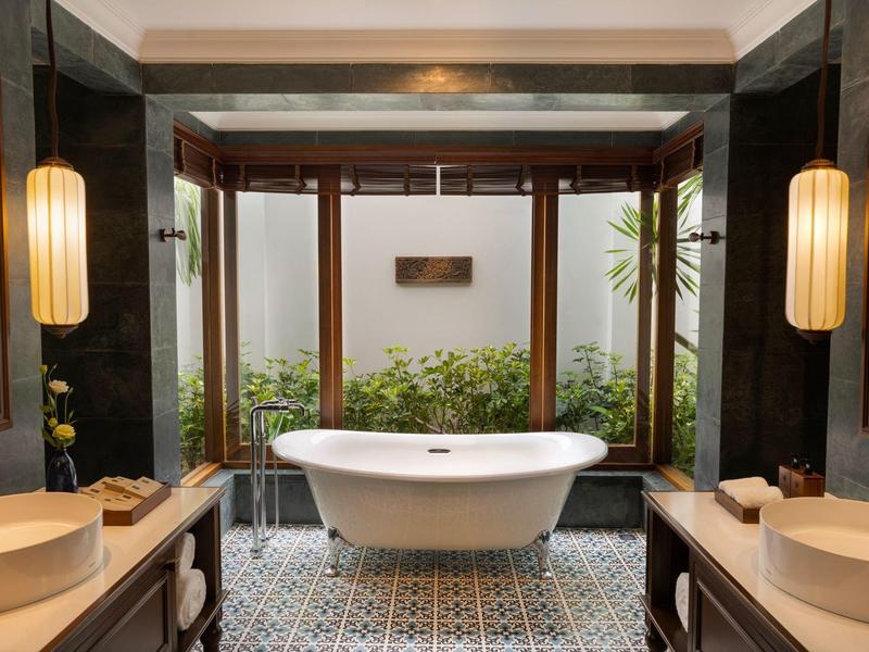 Luxuriöses Badezimmer mit freistehender weißer Badewanne, Holzakzenten und großen Fenstern.