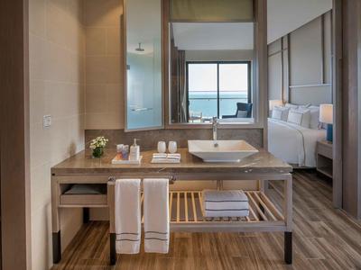 Moderní hotelová koupelna se dřevěnou skříňkou a výhledem do pokoje.