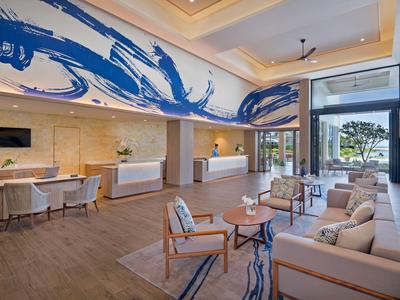 Moderner Hotellobby mit blauer kunstvoller Wandmalerei, bequemen Sesseln und Fenster mit Blick nach draußen.