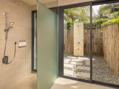 Moderní koupelna se soukromou sprchou uvnitř i venku obklopenou bambusem.