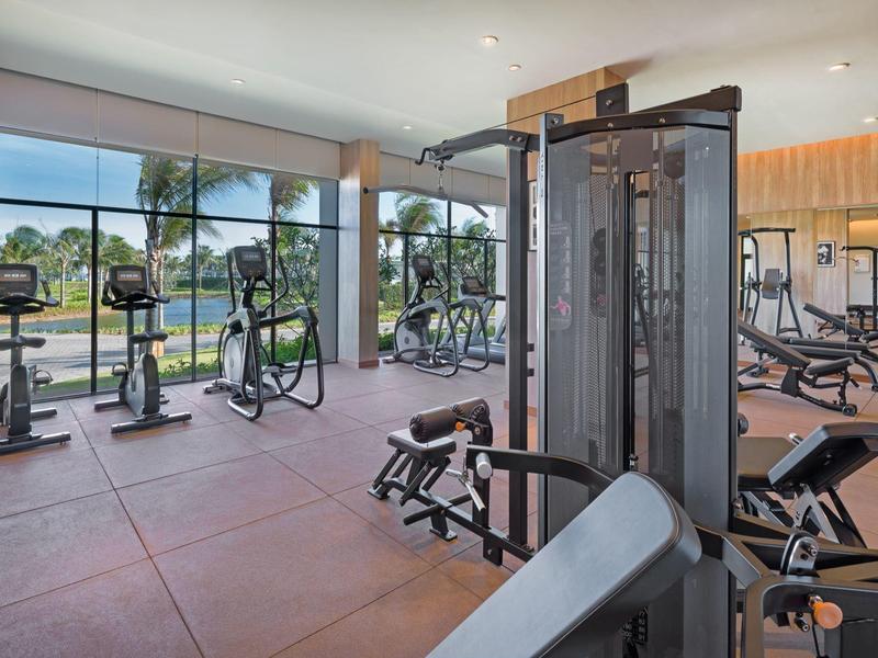 Moderní posilovna s velkými okny a různými stroji.