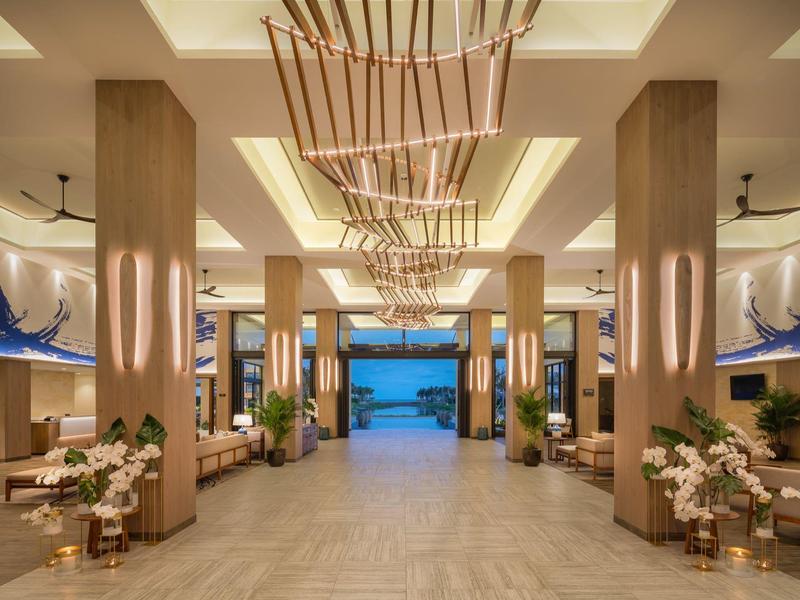 Prostorná hotelová hala s moderním zařízením a výhledem na moře v dálce.