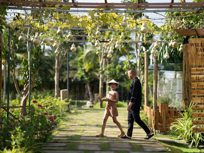 Pár procházející zahradou s pergolou a zavěšenými rostlinami.