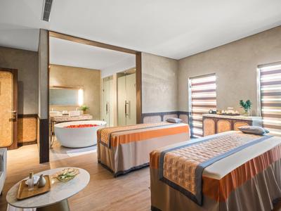 Lichte massageruimte met twee tafels, een bijzettafel en uitzicht op de badkamer.