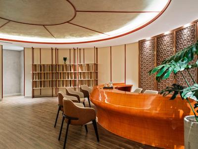 Moderne hotellounge met oranje receptiebalie en zitplaatsen.