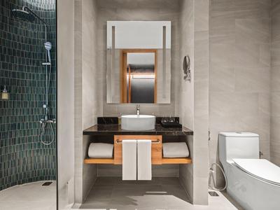 Moderne badkamer met wastafel, spiegel, douche en toilet in neutrale kleuren.