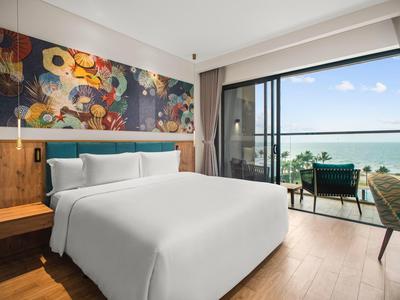 Modern hotelkamer met groot bed en zeezicht vanaf het terras.